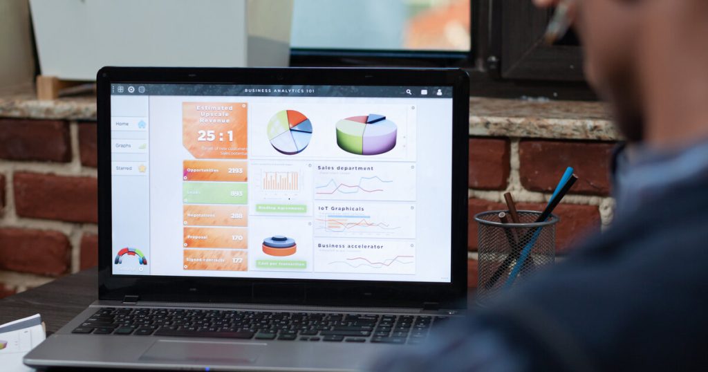 Analyst reviewing a business analytics dashboard with charts and KPIs on a laptop screen