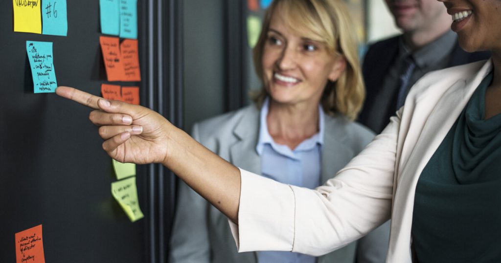A team pointing at sticky notes on a board while turning a customer journey map into action items