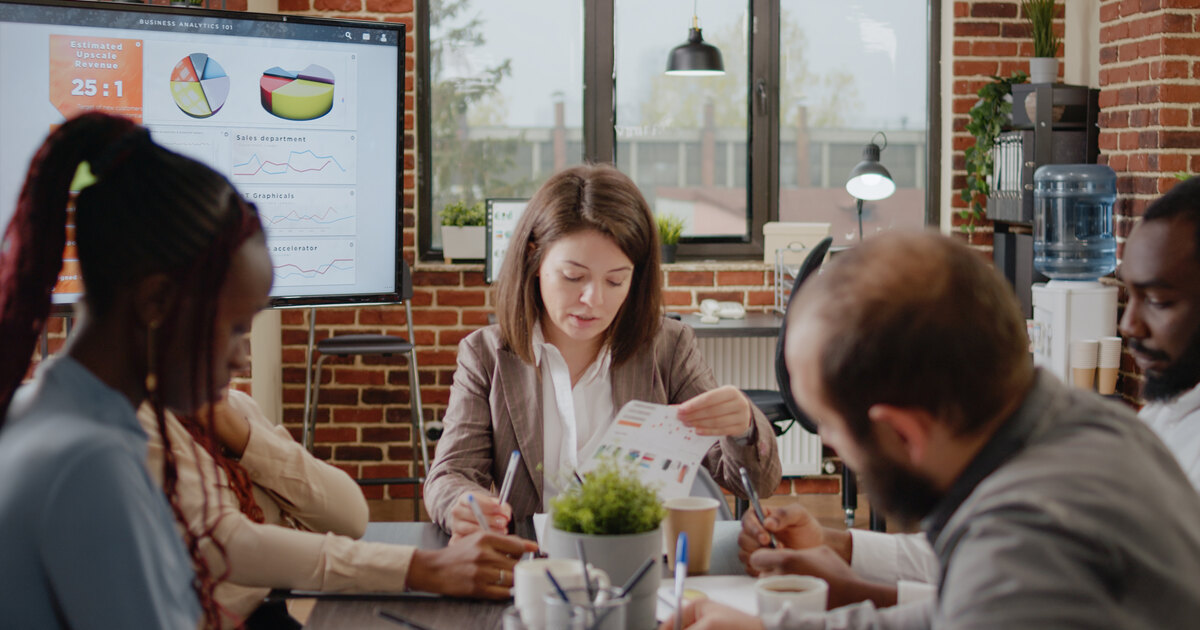 Diverse marketing team in an office reviewing analytics charts and reports to evaluate which content tactics actually work